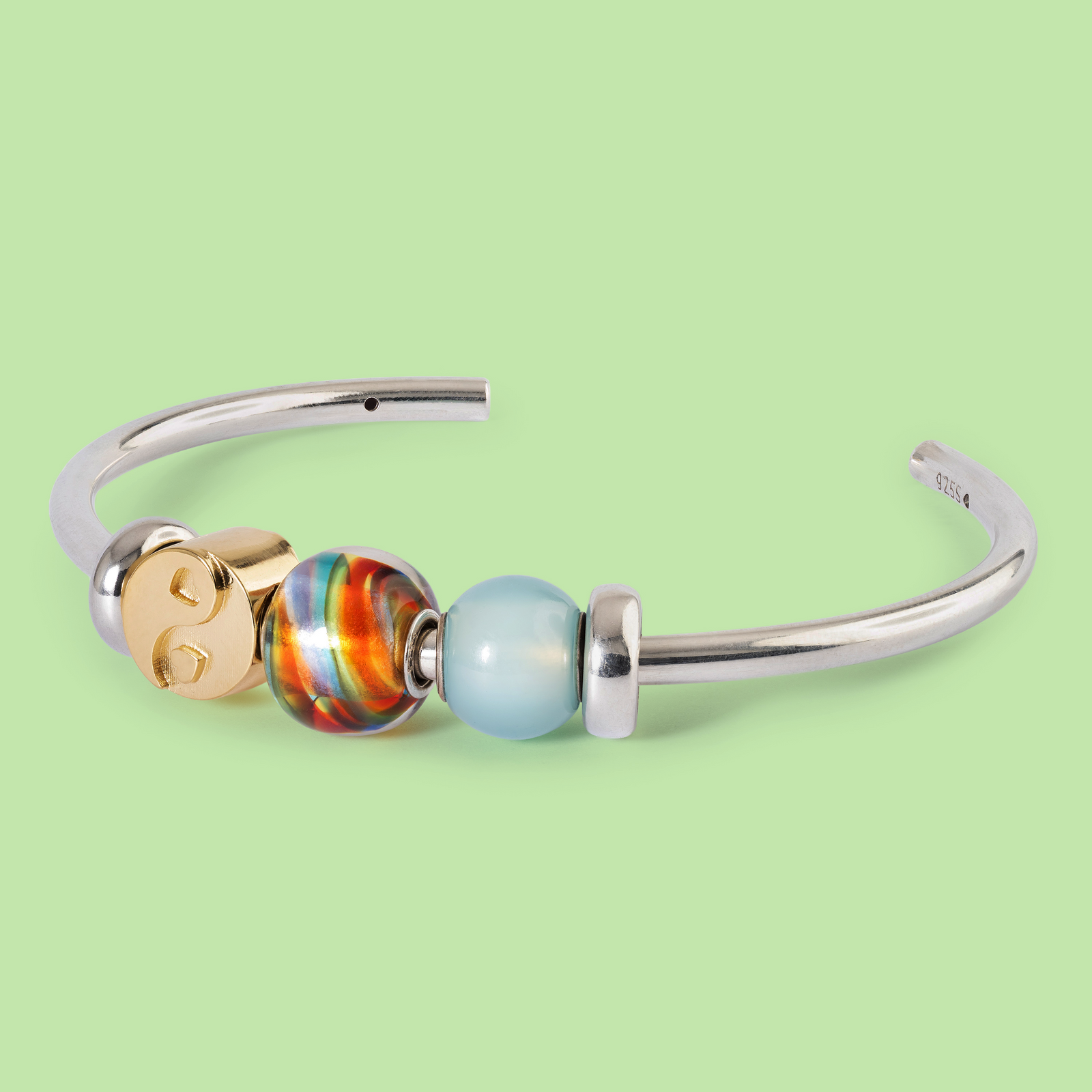 Silver bracelet with colorful beads on a light green background