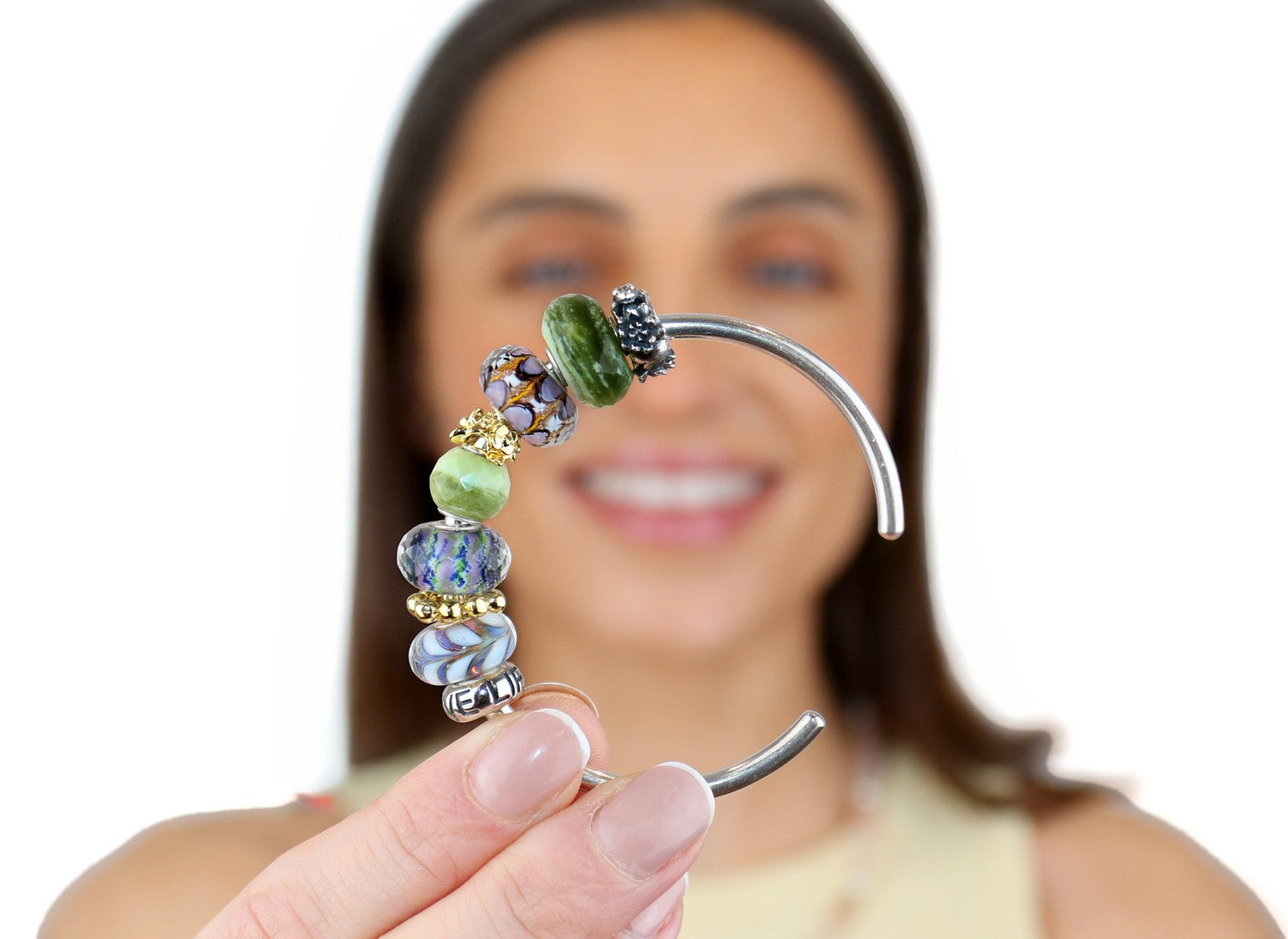 Person holding a decorative earring with beads against a white background
