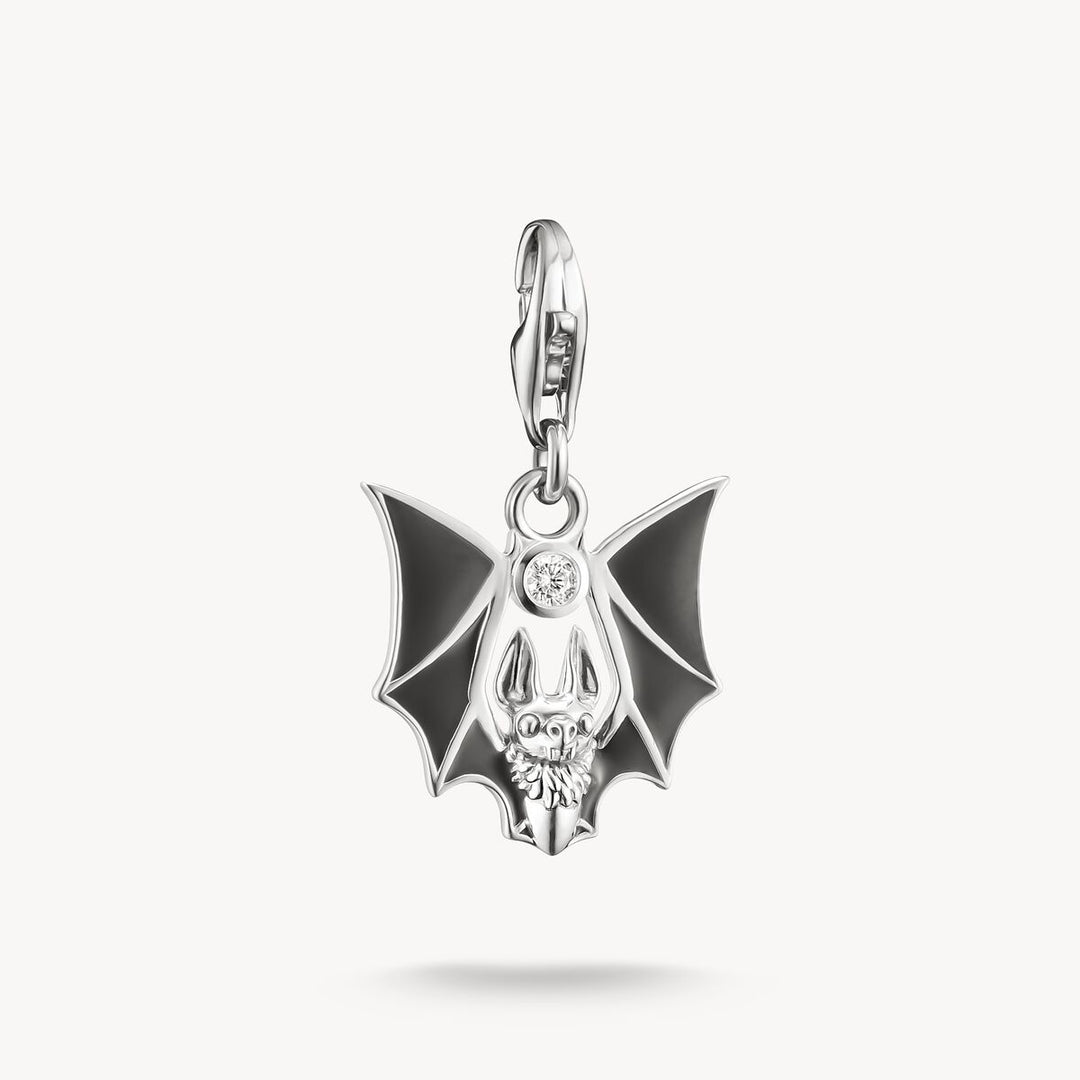 Silver pendant with black bat design on a white background