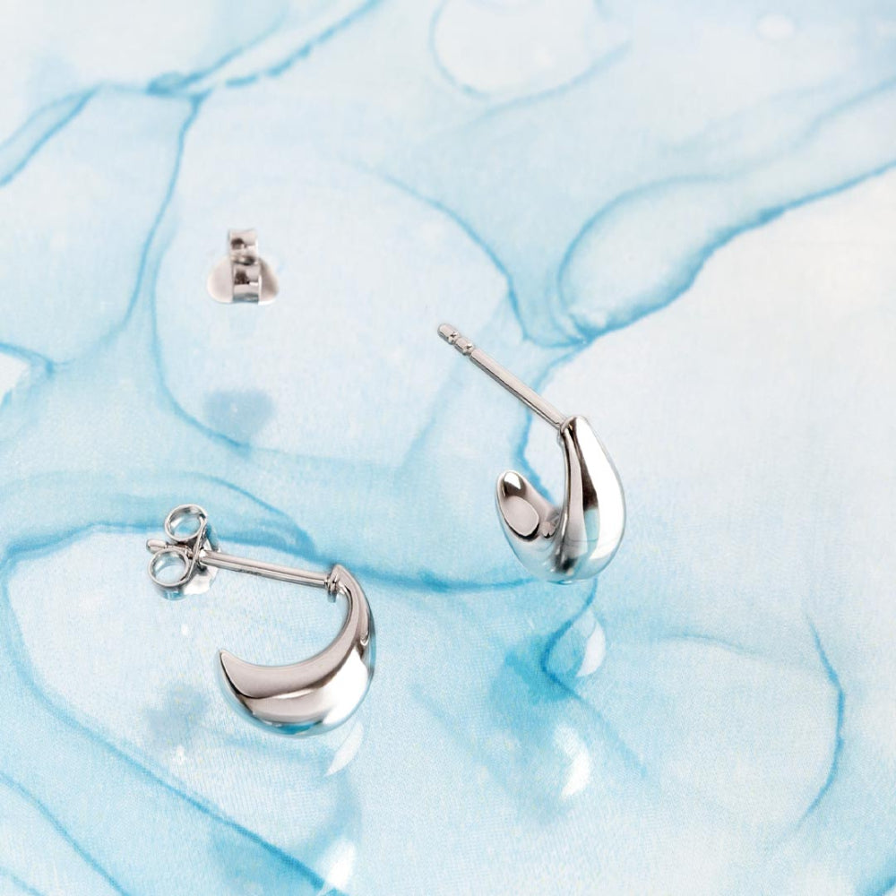Silver moon-shaped earrings on a light blue marble background