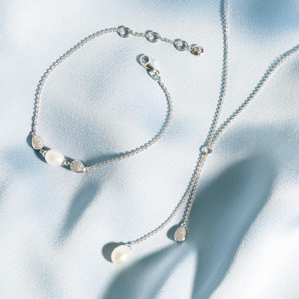 Silver necklace with pearls on a light blue fabric background