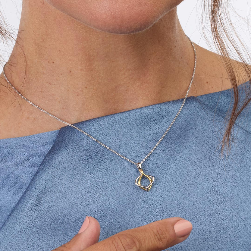 Necklace with a gold pendant worn by a person against a blue background