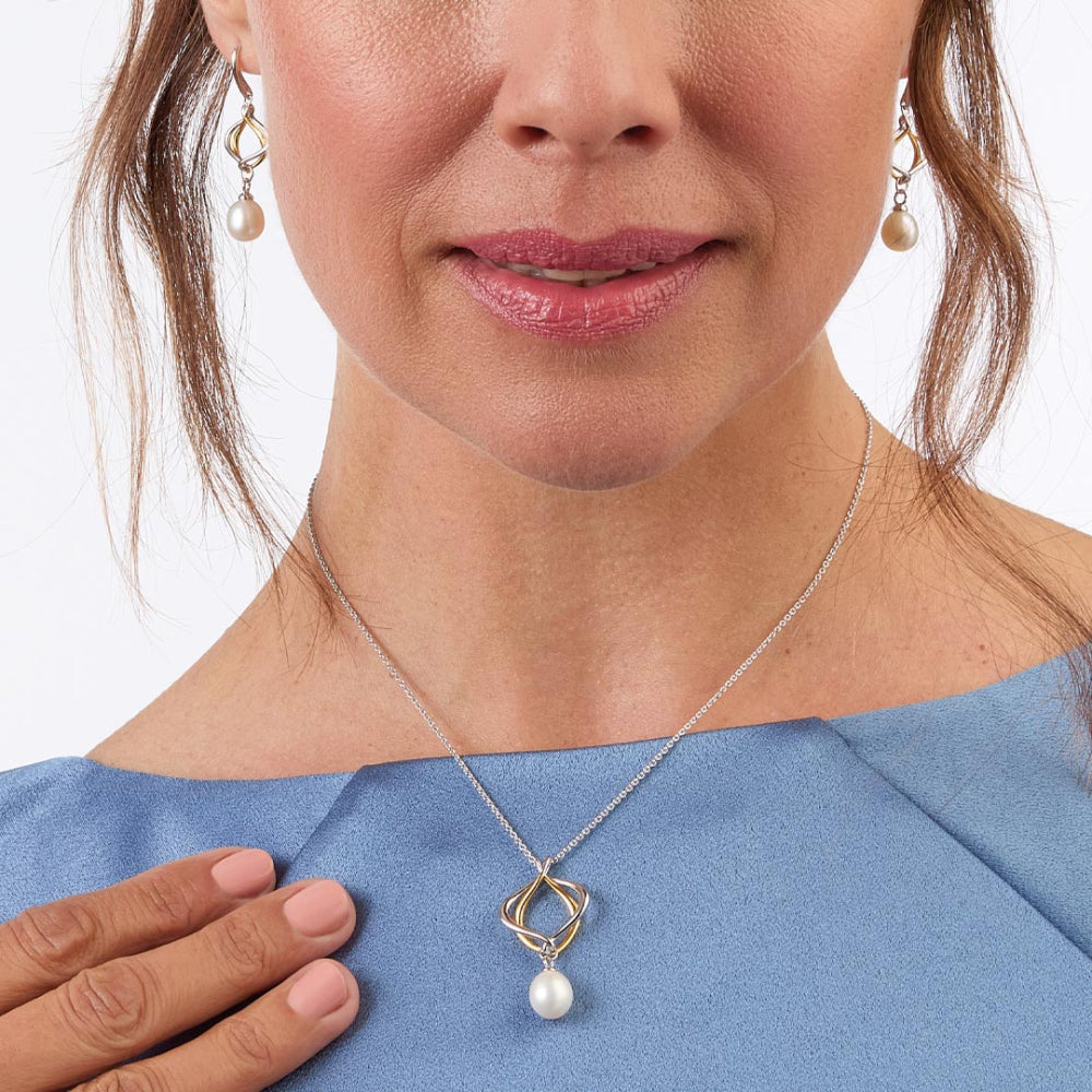 Woman wearing a silver necklace with a pearl pendant on a white background