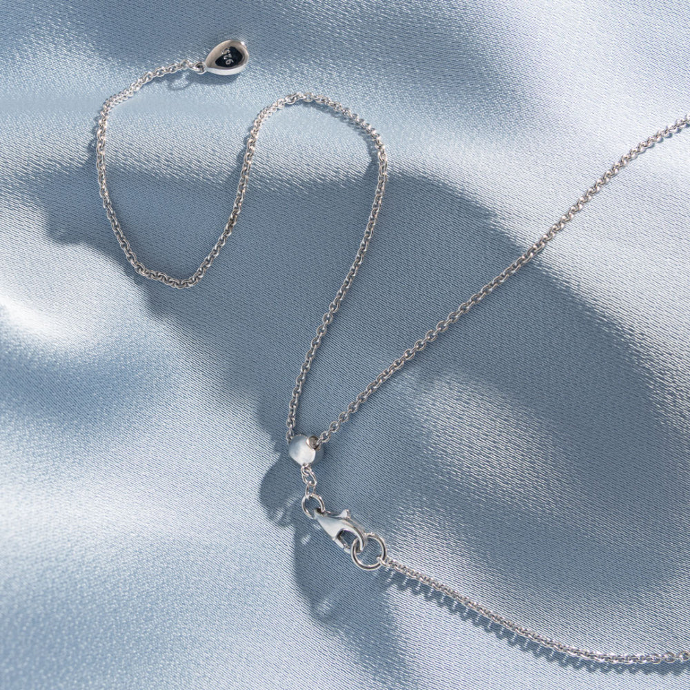 Silver necklace with a clasp on a light blue fabric background