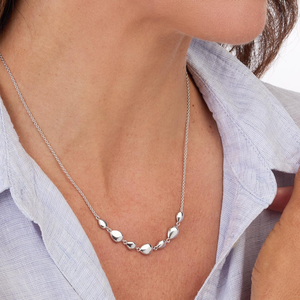 Silver necklace worn by a person with a light blue shirt