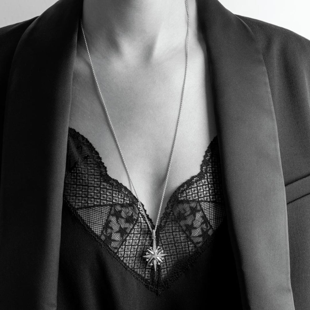 Mannequin wearing a black lace garment with a silver necklace featuring a star pendant.