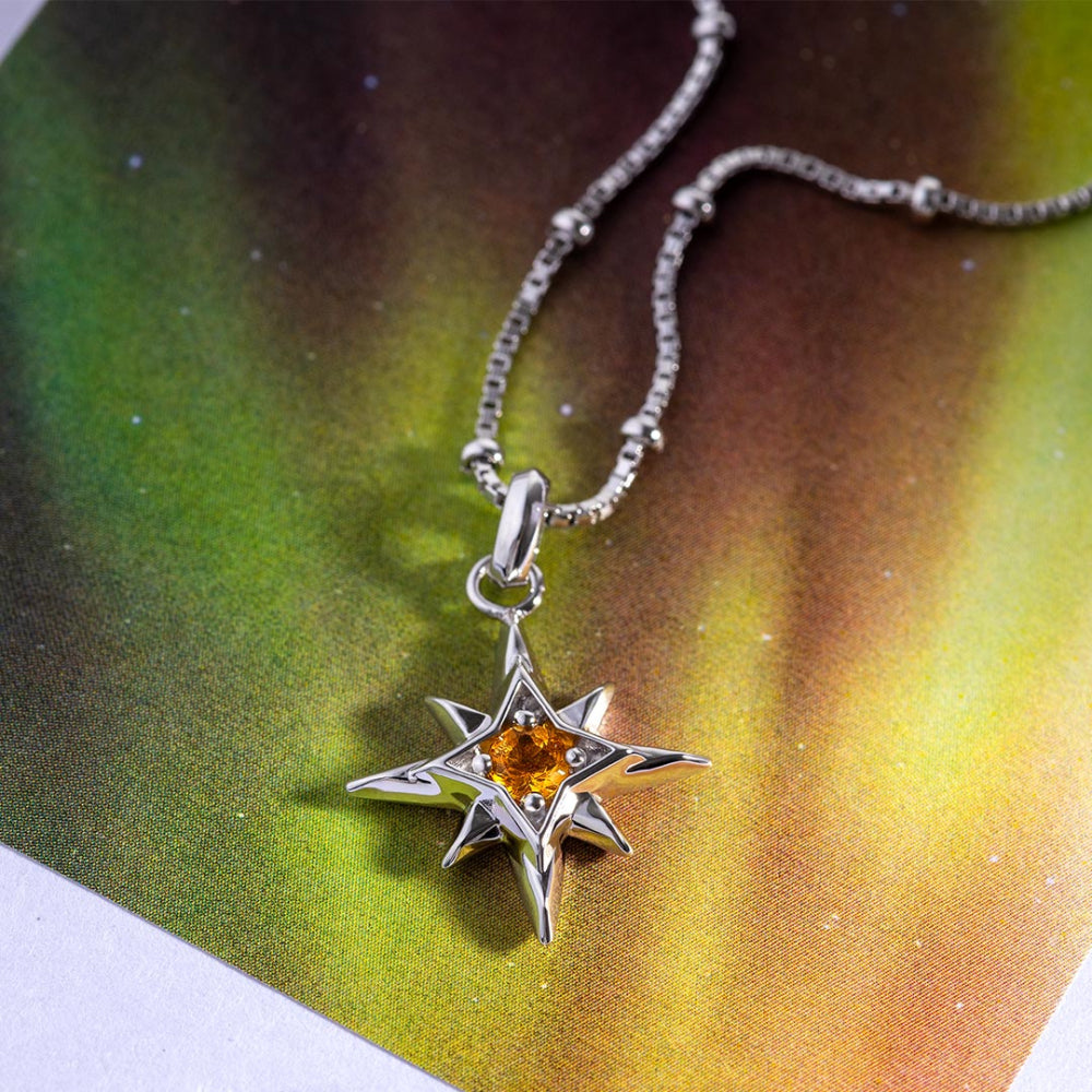 Silver star-shaped pendant with a yellow gemstone on a colorful background