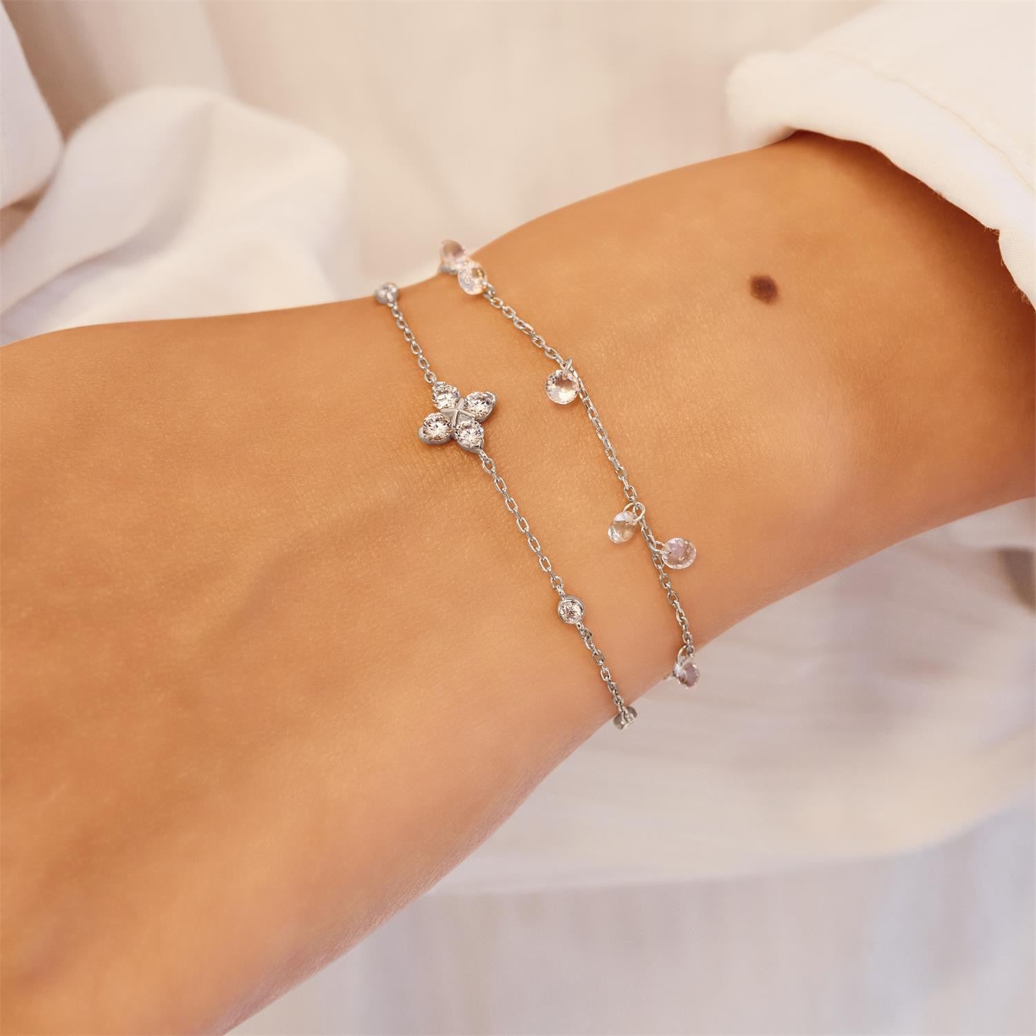 Silver bracelet with small beads on a wrist against a white background