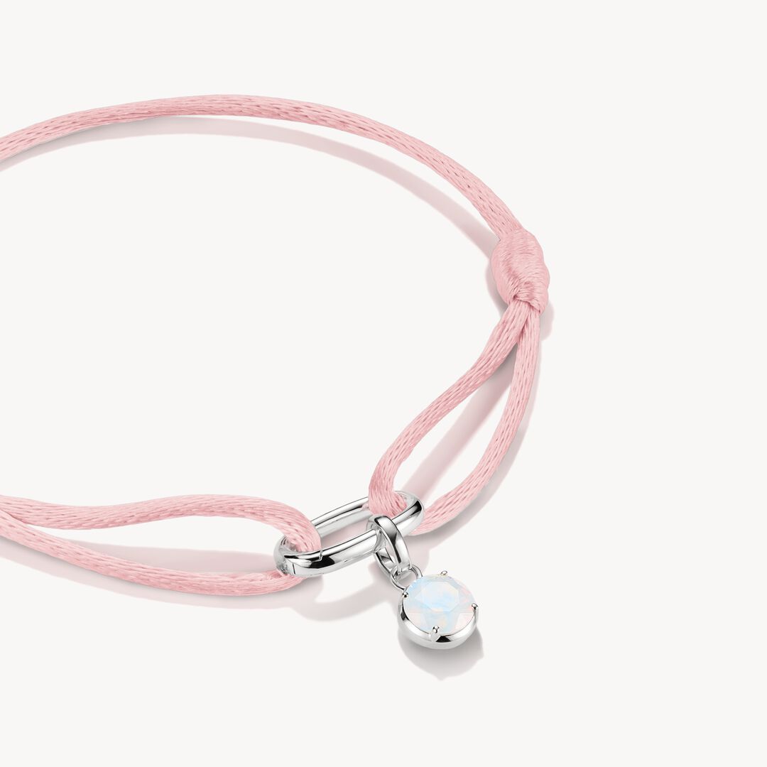 Pink cord bracelet with a silver clasp and pendant on a white background