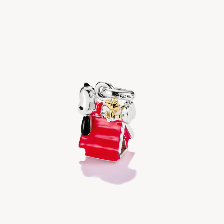 Charm resembling a character from 'Peanuts' with a red dress and yellow bow on a white background
