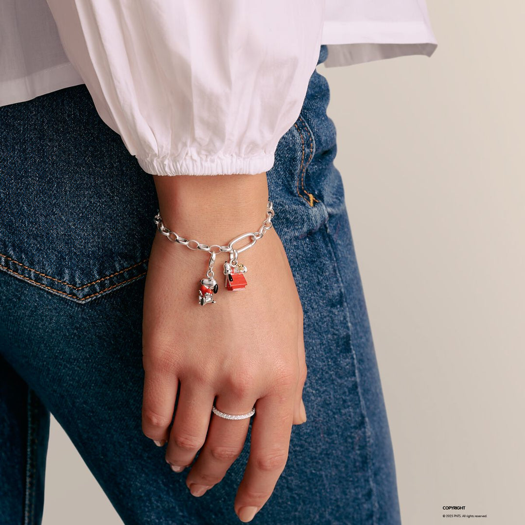 Person wearing a bracelet with charms on a plain background