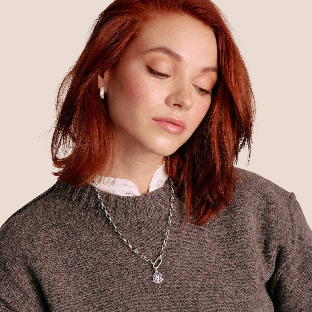 Woman wearing a gray sweater and necklace with a neutral background