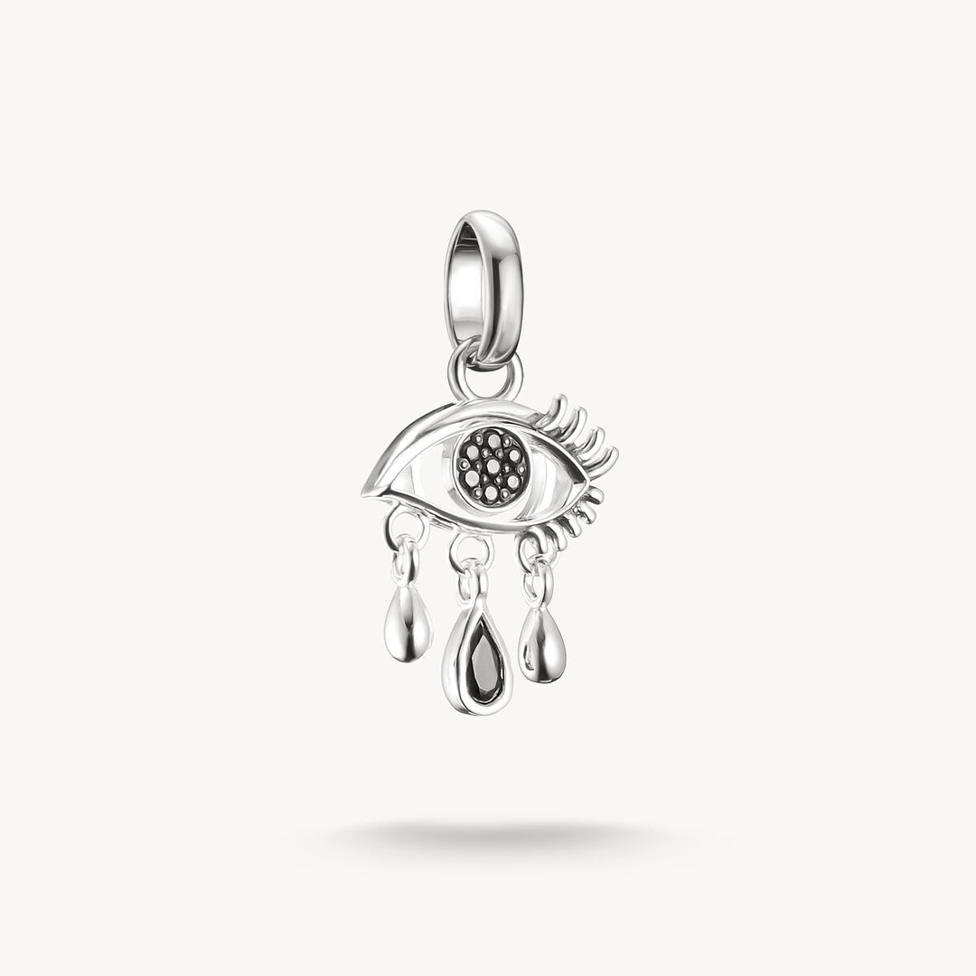 Silver eye-shaped pendant with a tear on a white background