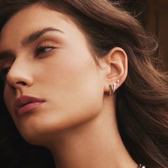 Close-up of a woman wearing gold hoop earrings with a blurred background