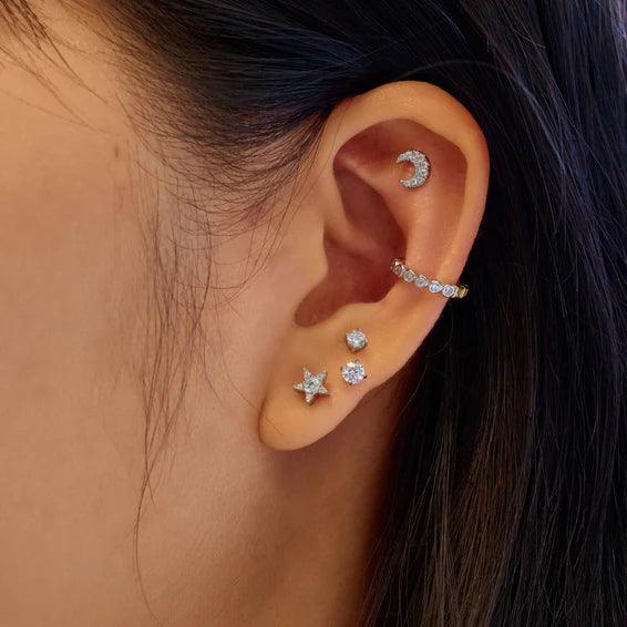 Close-up of an ear wearing multiple diamond earrings with a blurred background