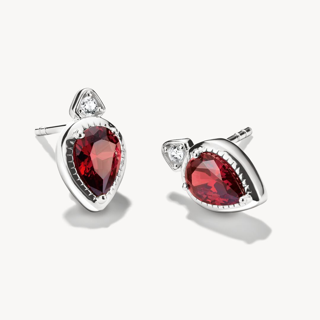 Pair of earrings with red gemstones and silver settings on a white background