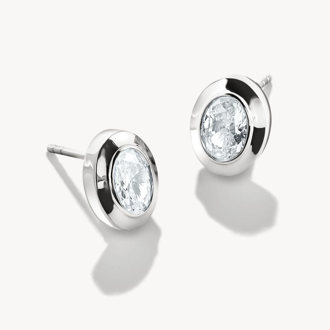 Pair of silver earrings with clear gemstones on a white background