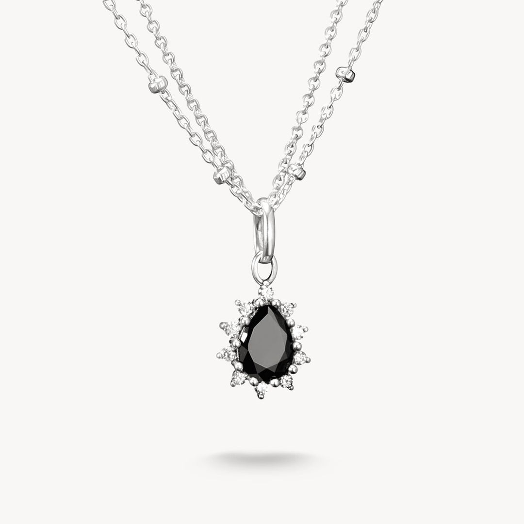 Silver necklace with a black teardrop pendant on a white background
