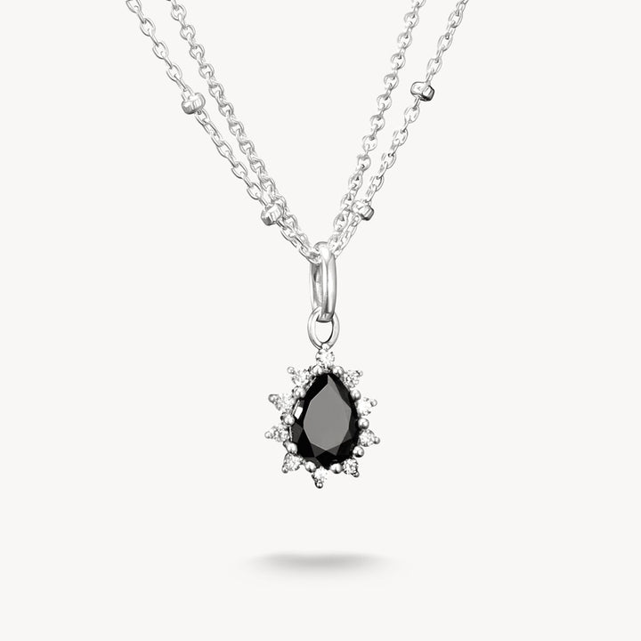 Silver necklace with a black teardrop pendant on a white background