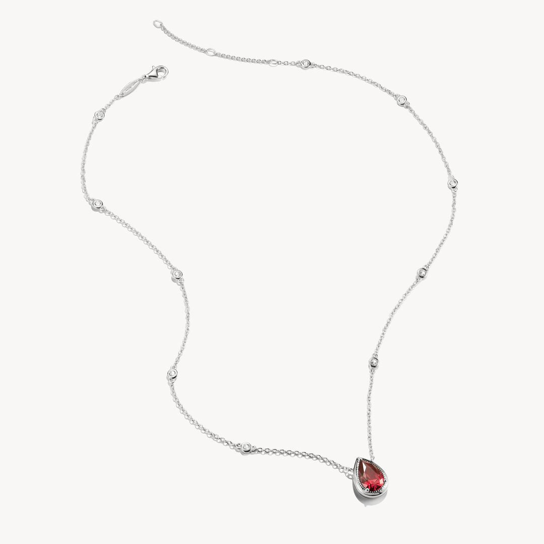 Silver necklace with a red teardrop pendant on a white background