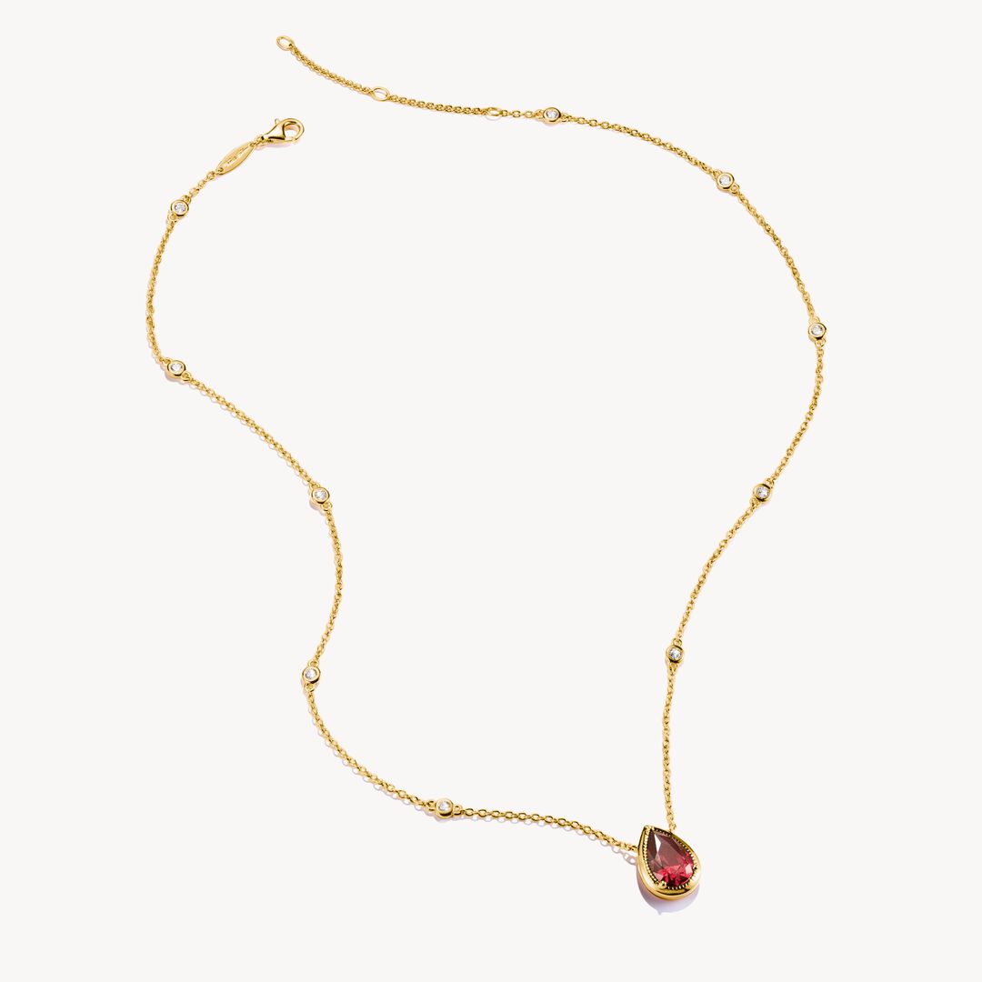 Gold necklace with a teardrop-shaped gemstone on a white background