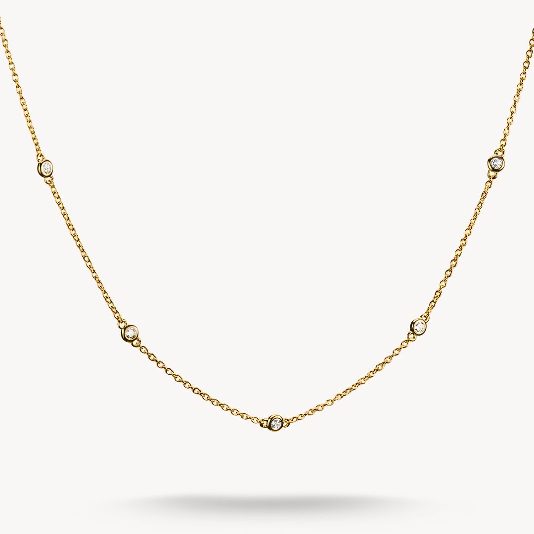 Gold necklace with small diamonds on a light gray background