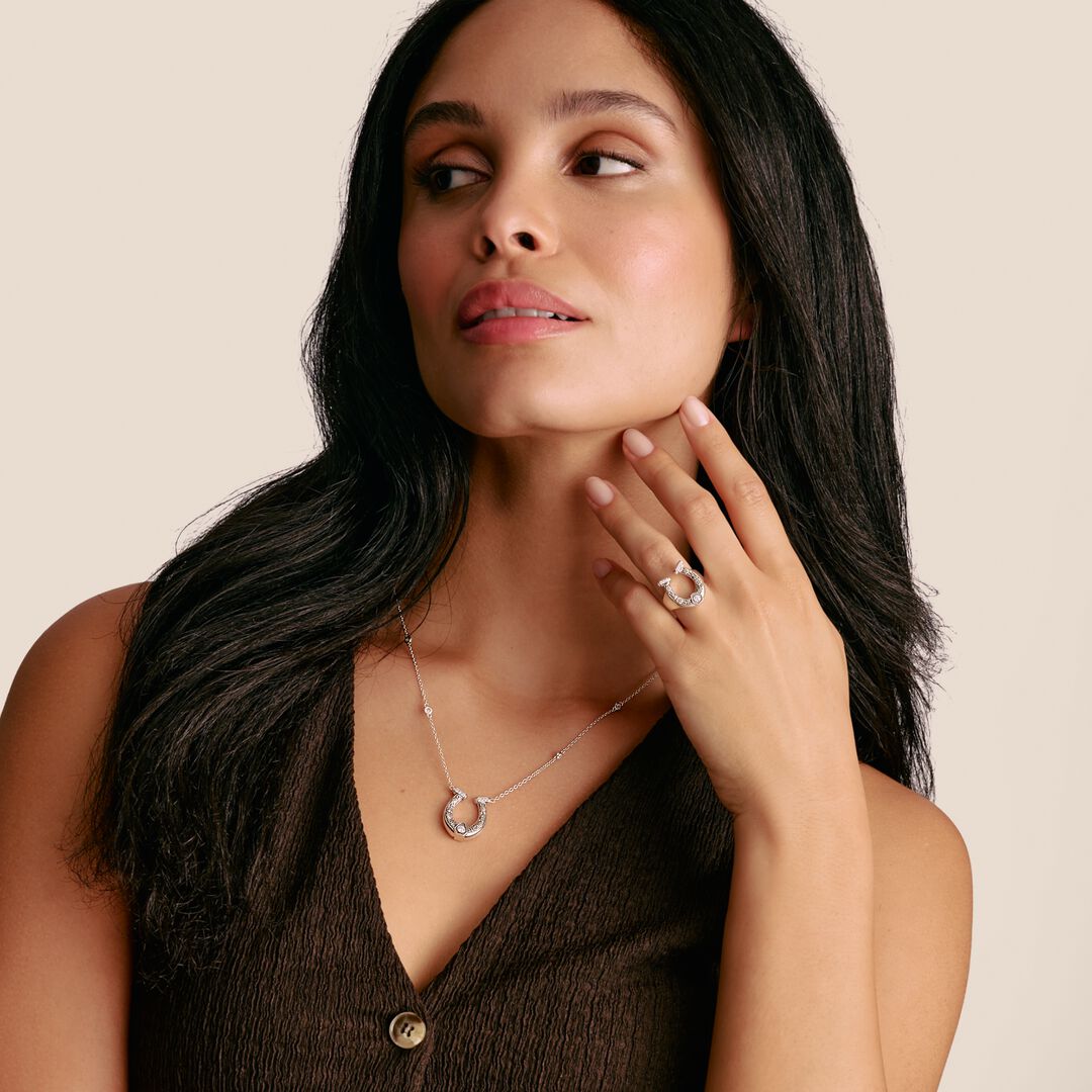 Woman wearing a necklace and ring on a beige background