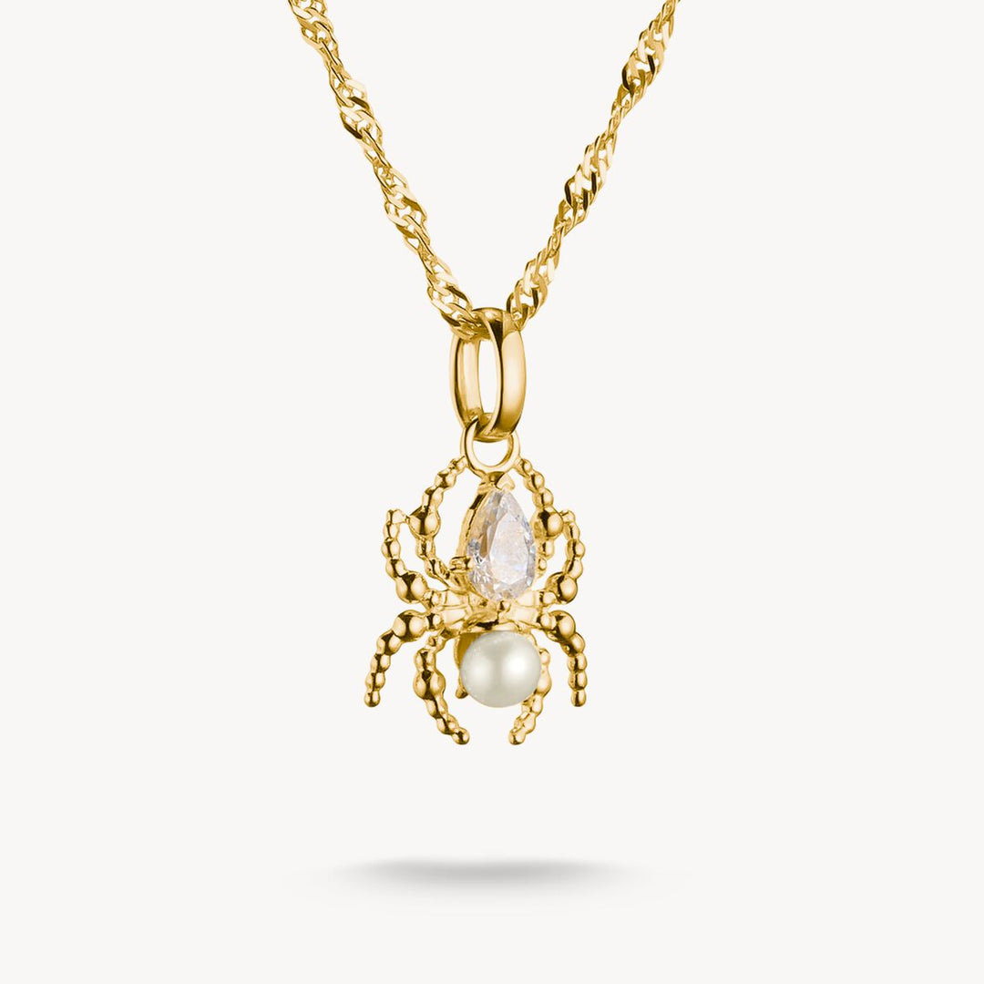 Gold pendant necklace with a central pearl and teardrop-shaped gemstone on a white background