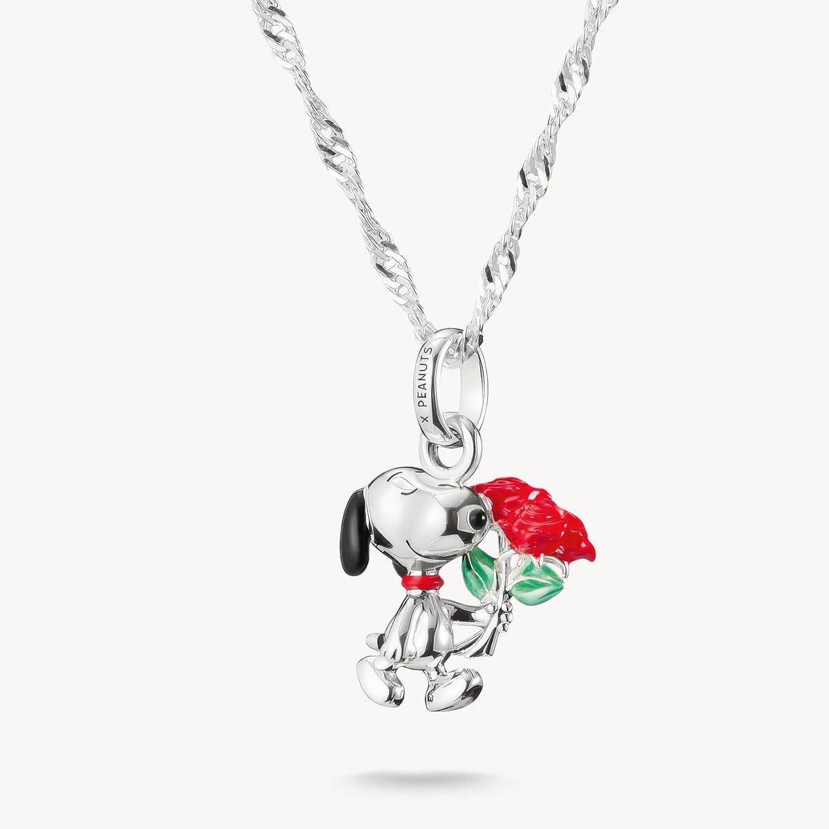 Silver pendant of a dog holding a red rose on a white background