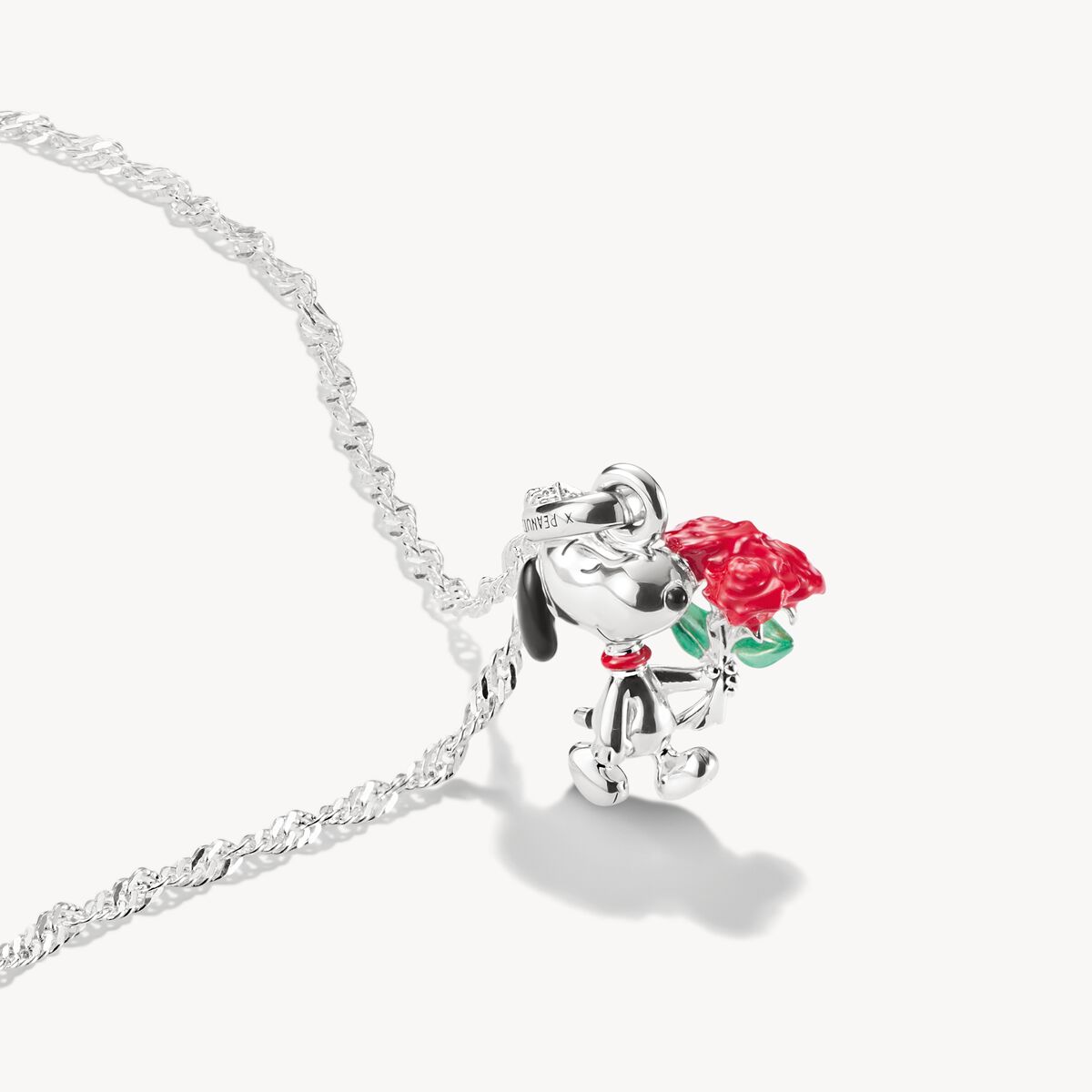 Silver dog charm with a red rose on a white background