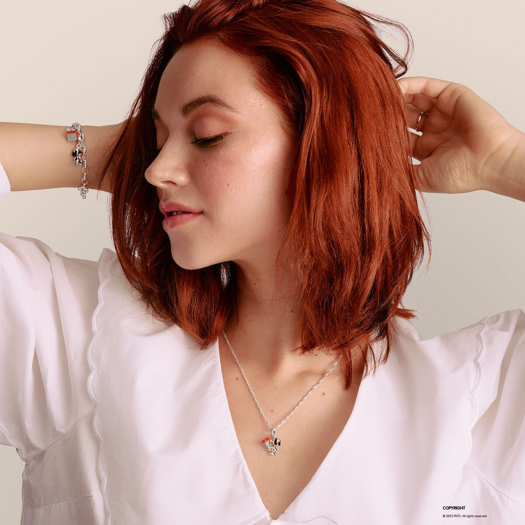 Woman with red hair wearing a white shirt and a necklace on a light background