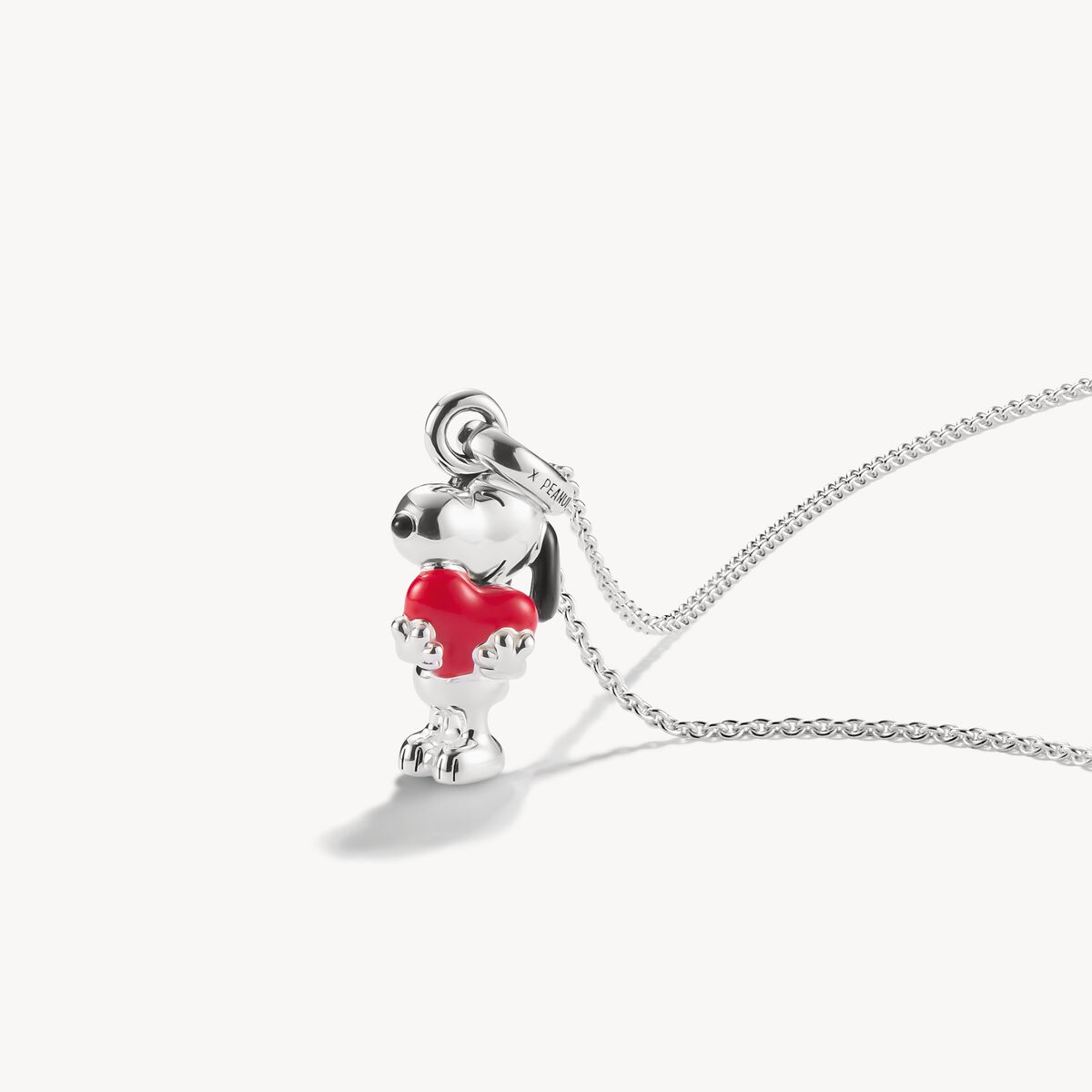 Silver pendant with a red heart on a white background