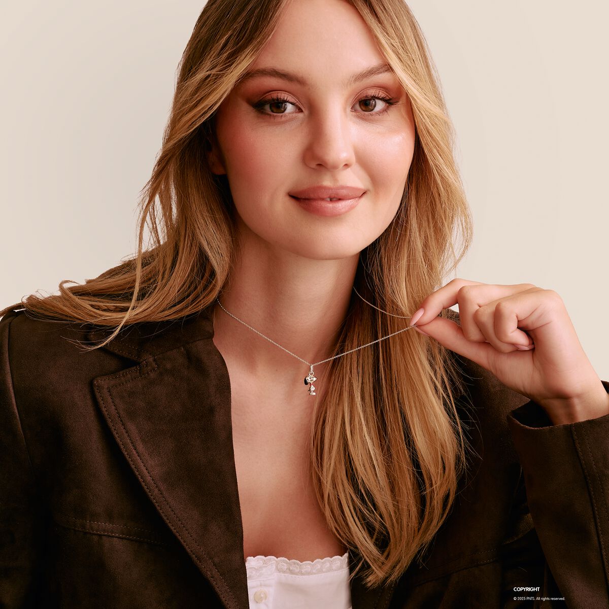 Woman wearing a necklace with a small pendant against a neutral background