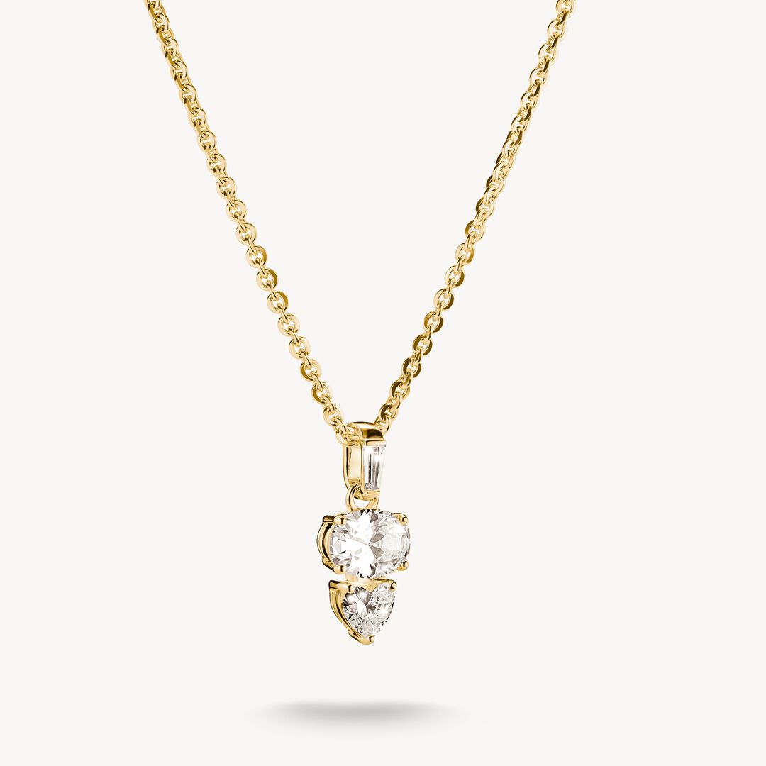 Gold necklace with a three-stone heart-shaped diamond pendant on a white background