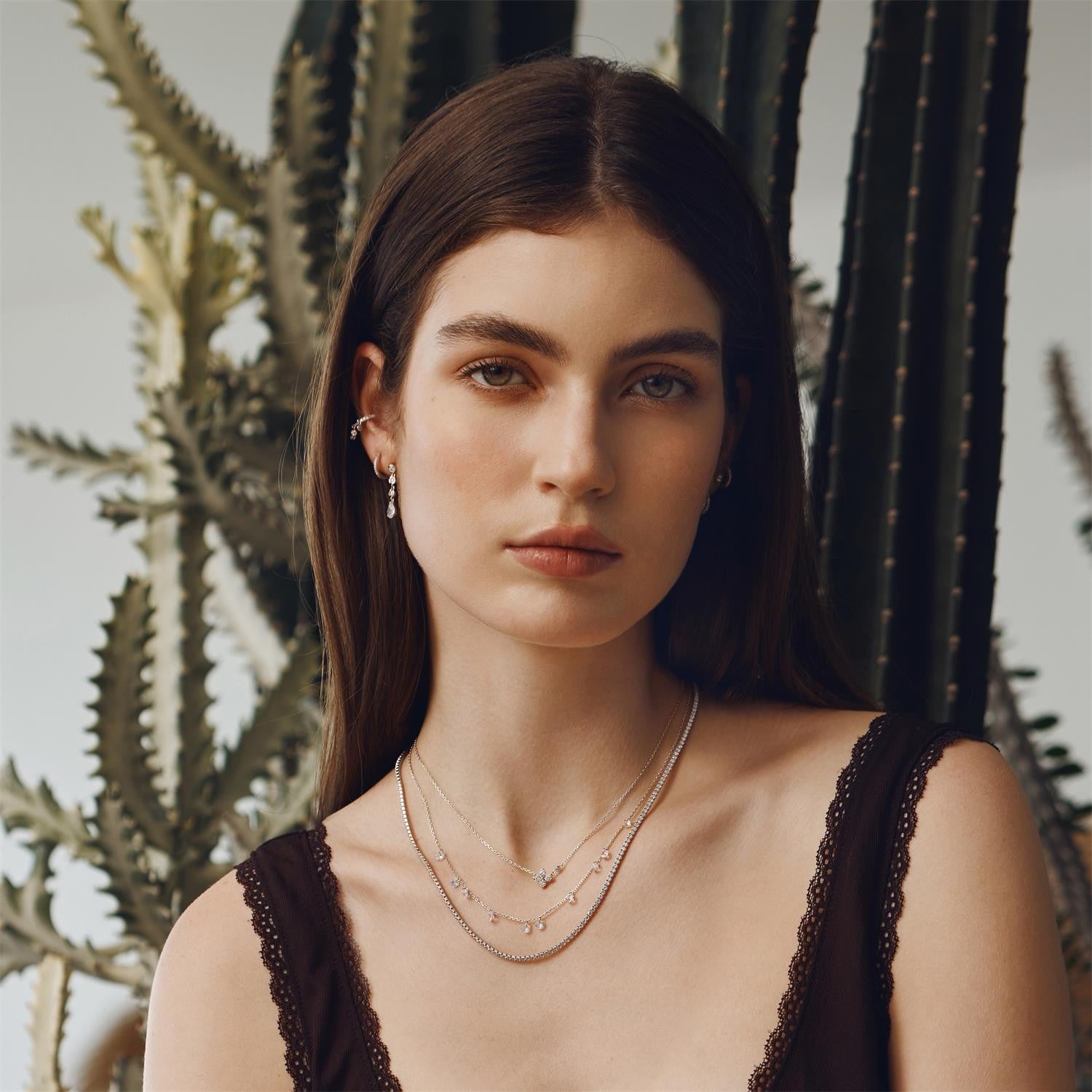 Woman wearing layered necklaces in front of cacti