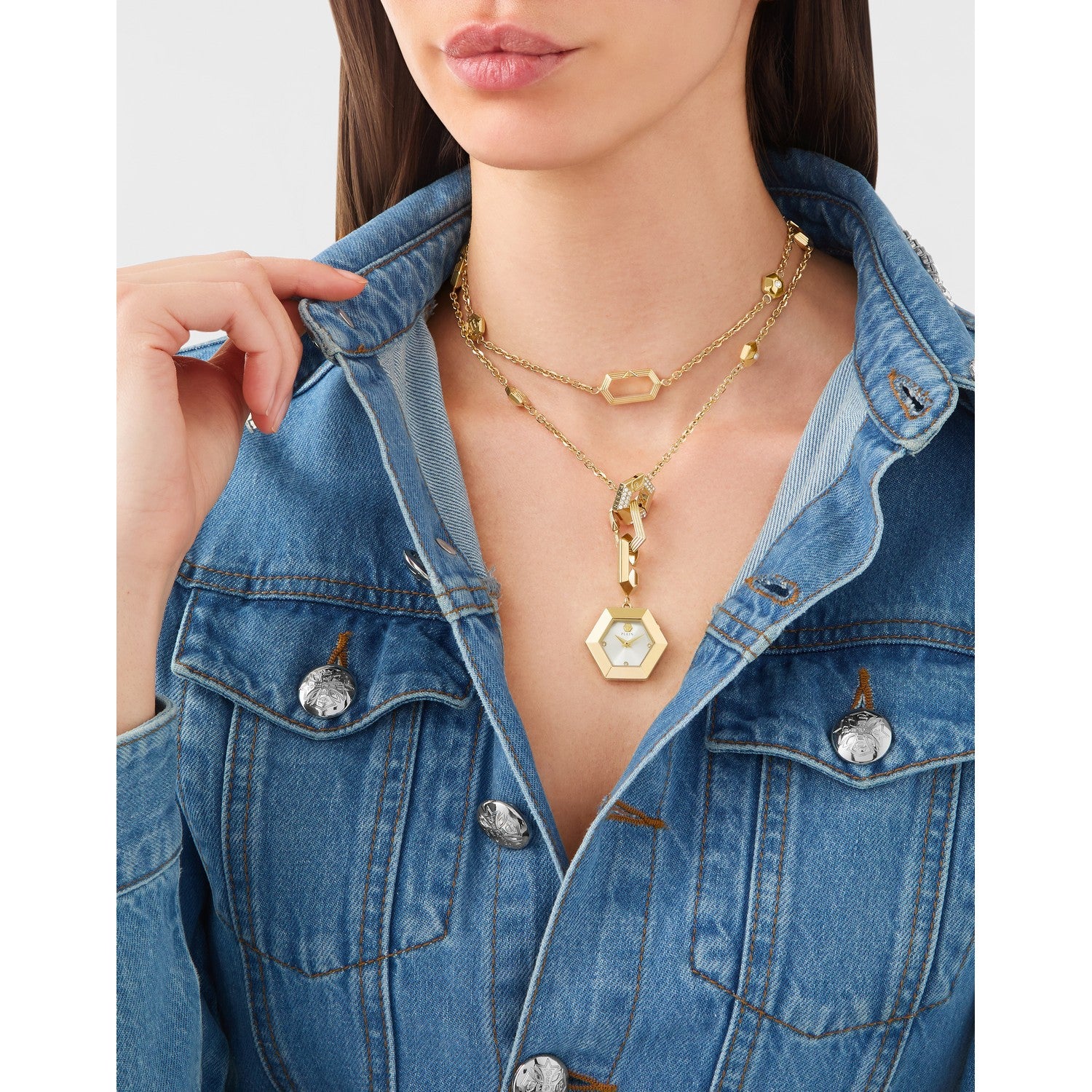 Woman wearing a gold necklace with a hexagonal pendant against a neutral background