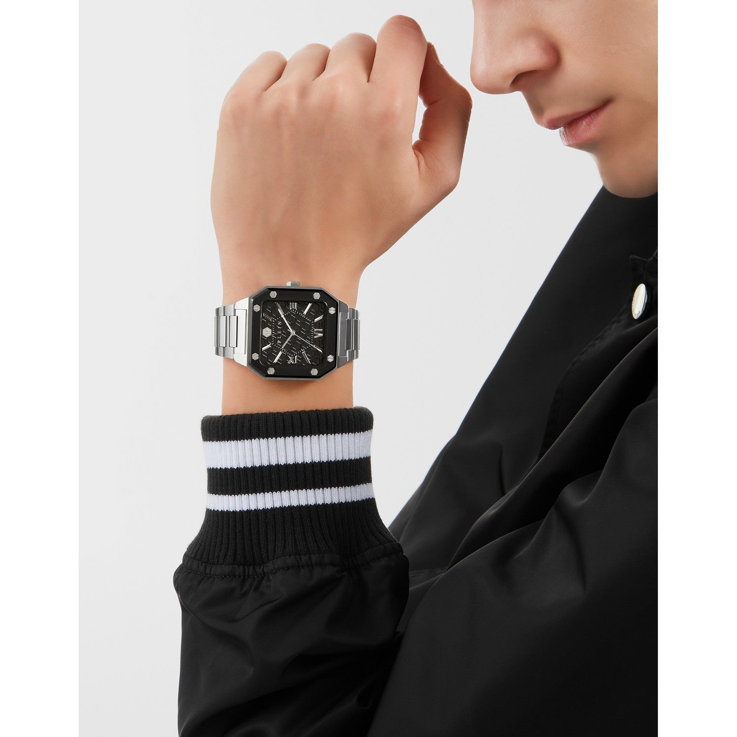 Person wearing a black watch with a white strap on a plain background