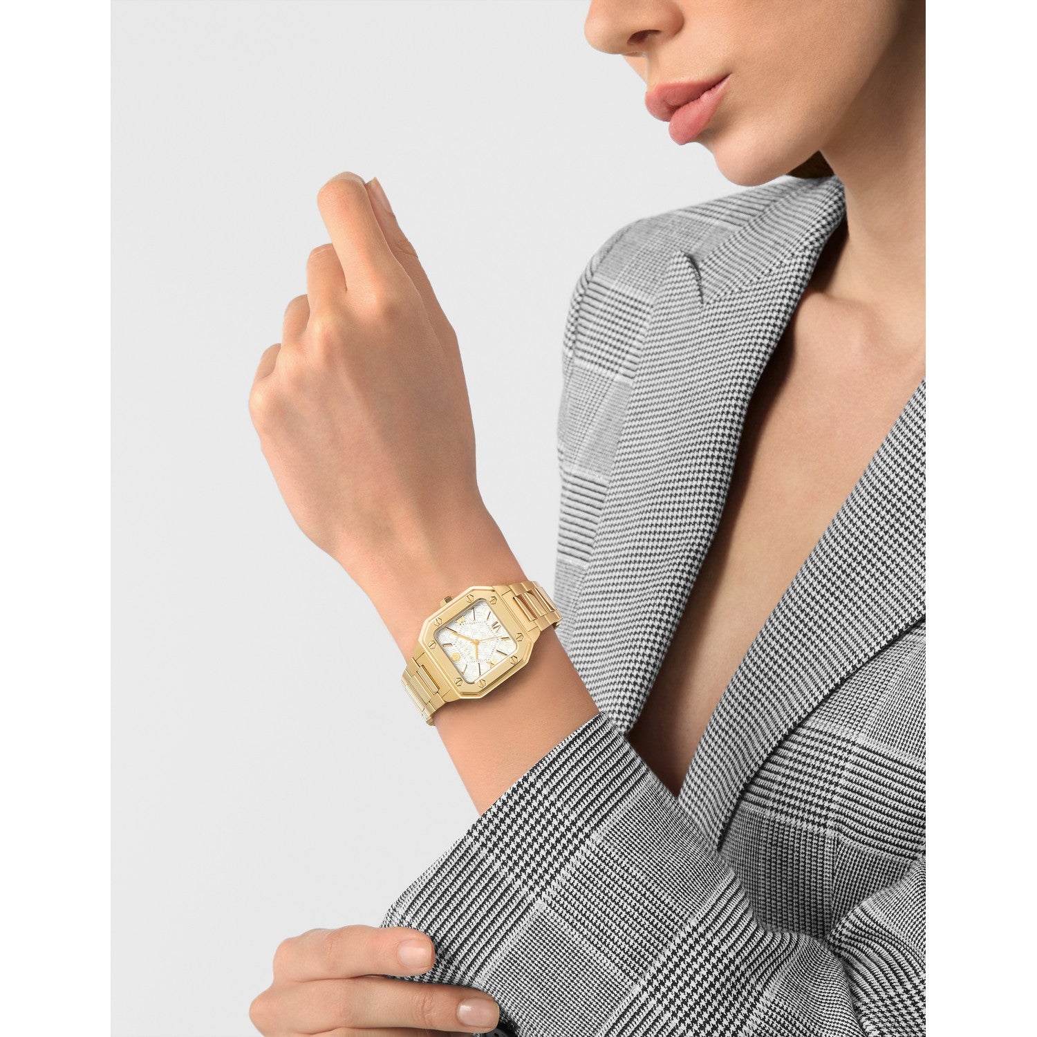 Gold watch on a wrist with a neutral background