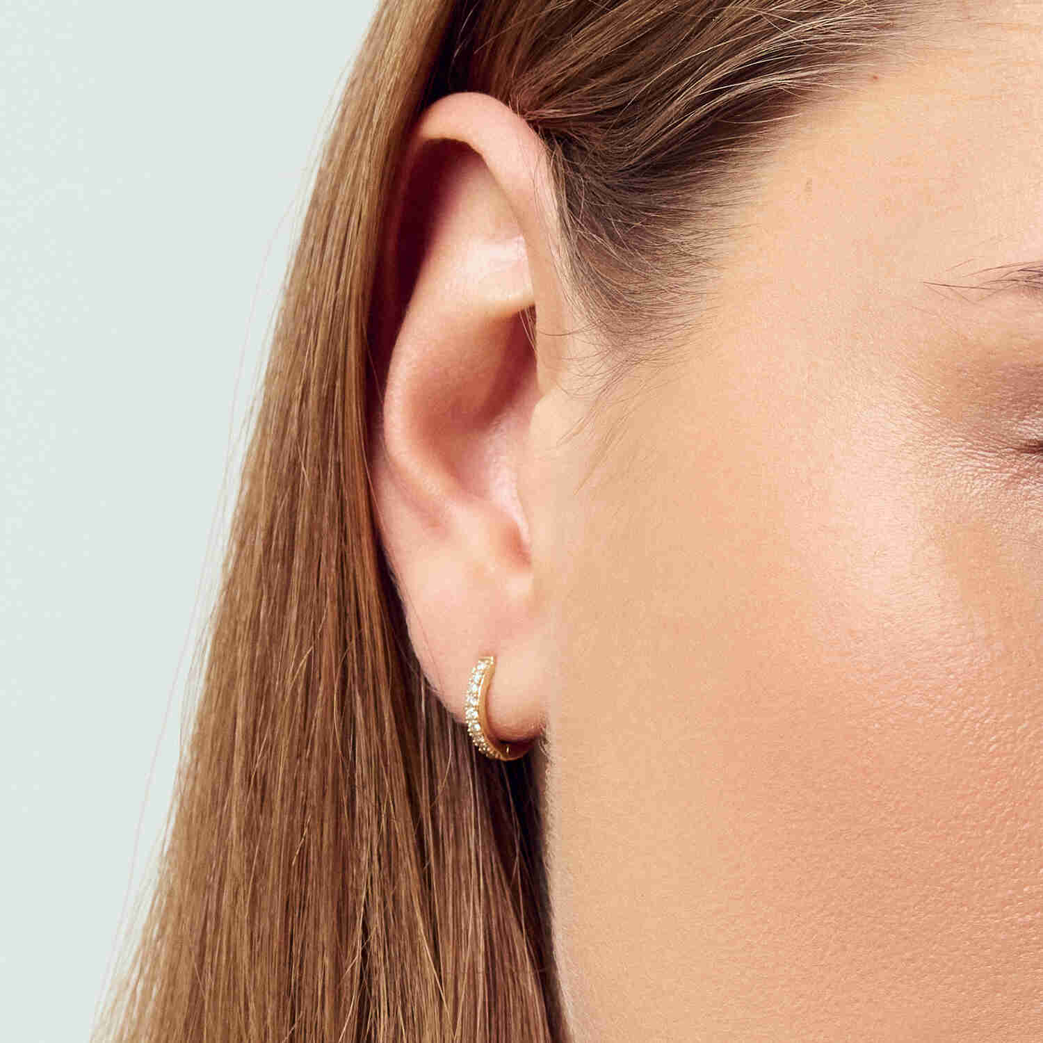 Luxury model wearing the 14k White Gold Alba Piccolo Single Diamond Earring SJ-E2510-WD-WG-1, highlighting the exquisite earring against the backdrop of a graceful style.