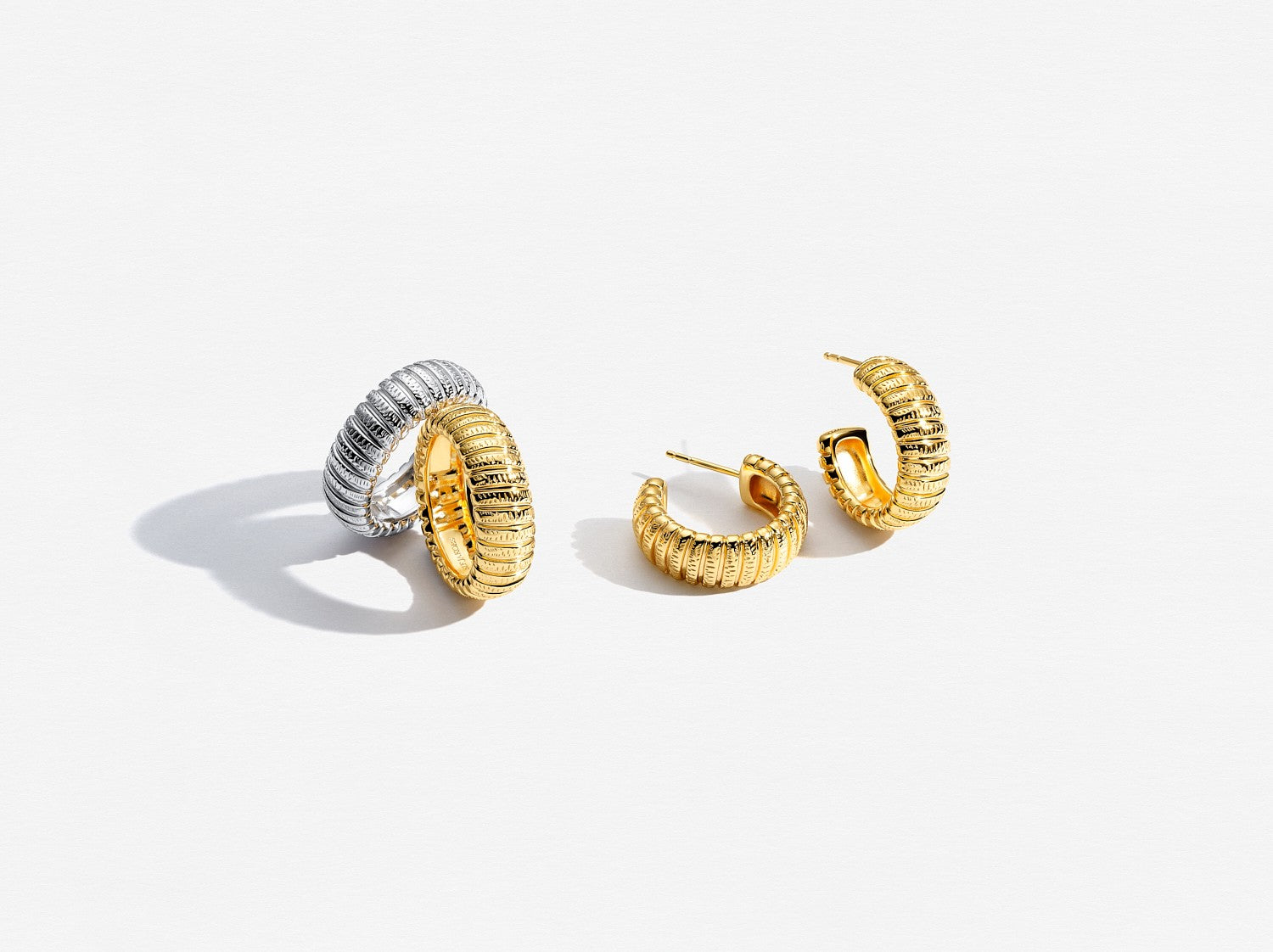 Pair of gold and silver hoop earrings on a light gray background