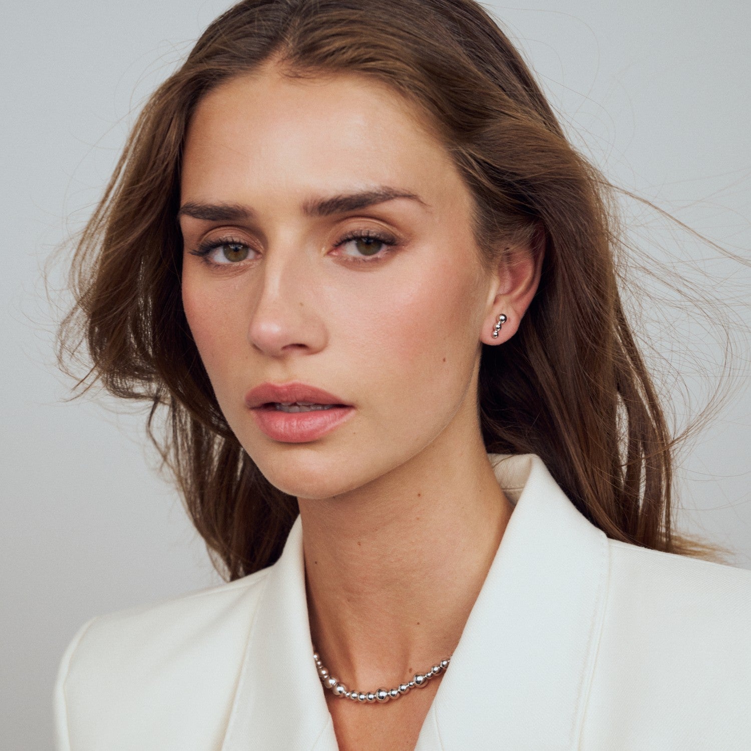 Woman wearing a white blazer with a plain background