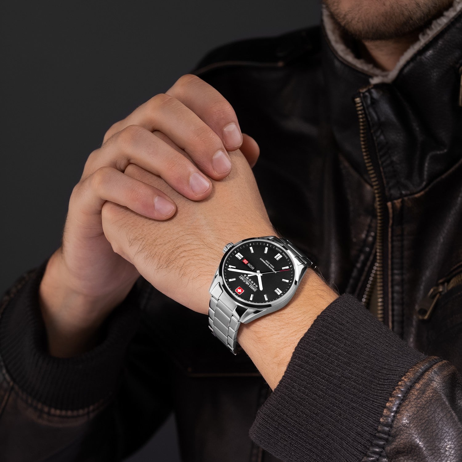 Person wearing a black watch with a silver strap on a dark background