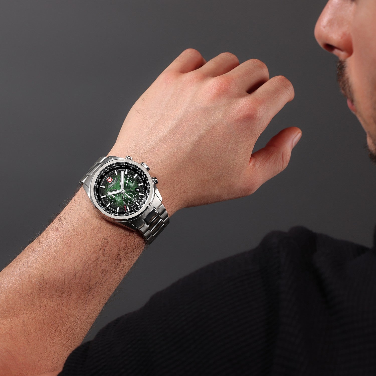 Man wearing a silver watch with a dark face on a gray background