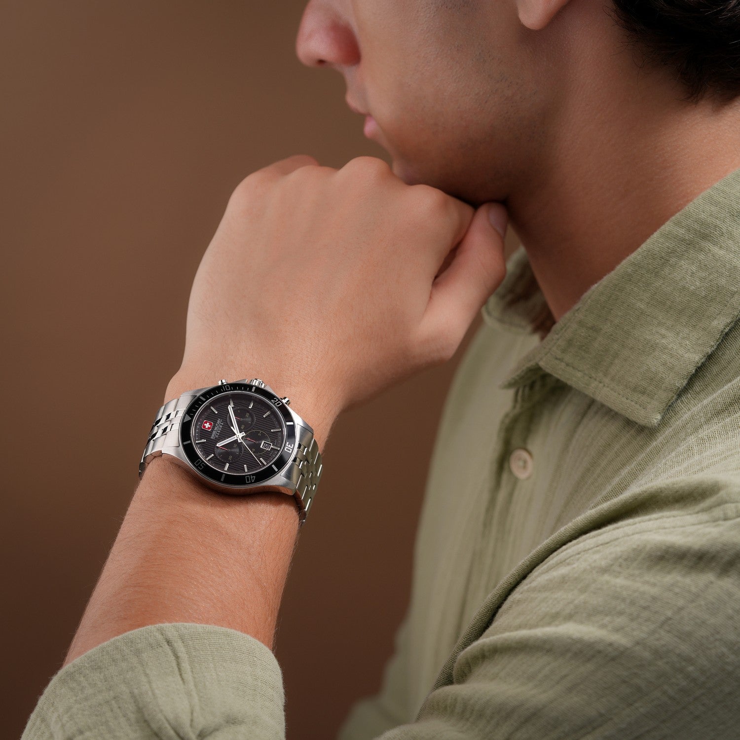 Man wearing a watch on his wrist with a brown background