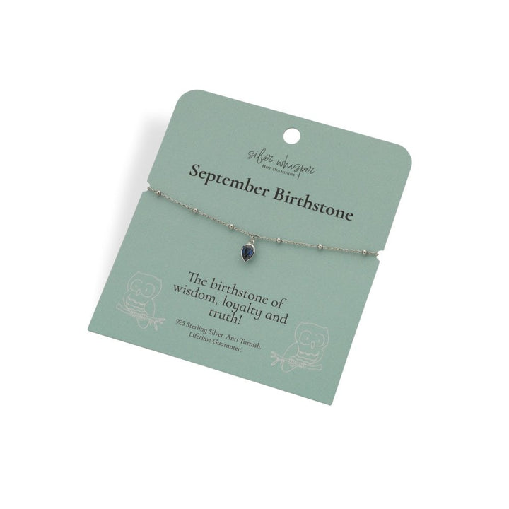 Silver bracelet with a heart-shaped gemstone on a green card with text about September birthstone.