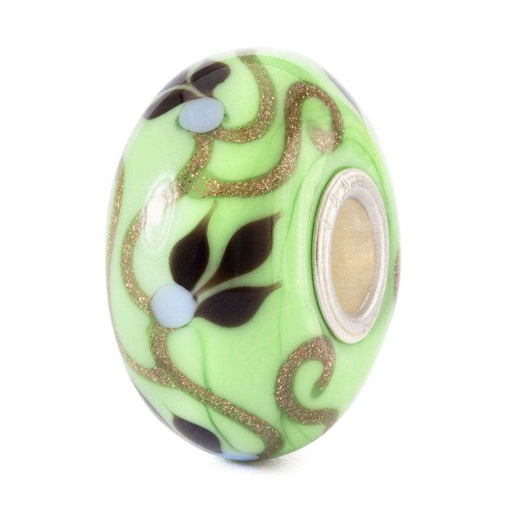 Decorative green bead with floral patterns on a white background