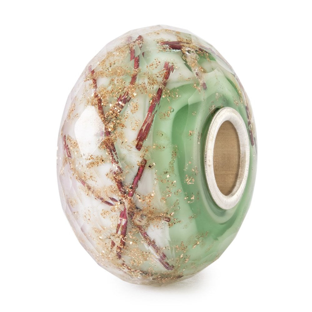 Decorative bead with green, white, and gold patterns on a white background