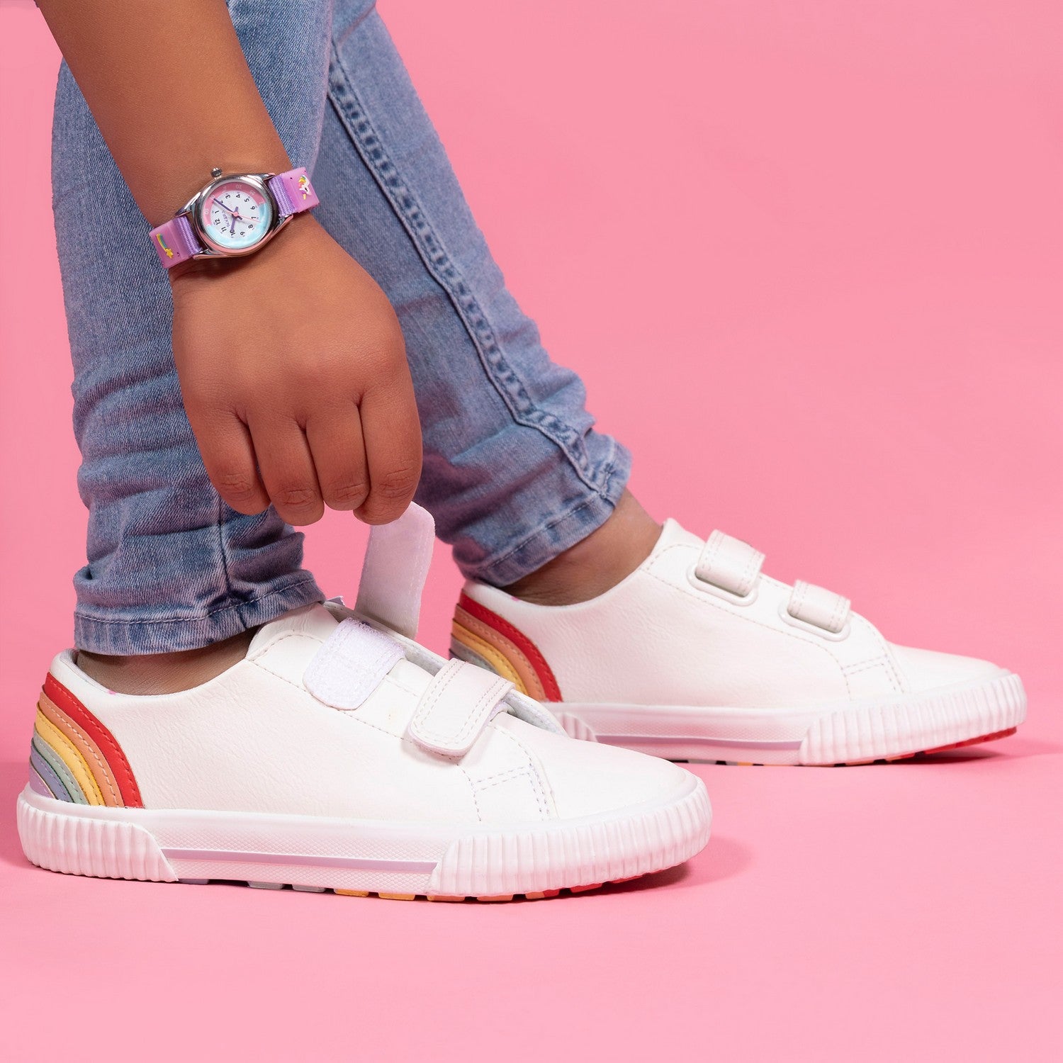 White sneakers with rainbow stripes on a pink background