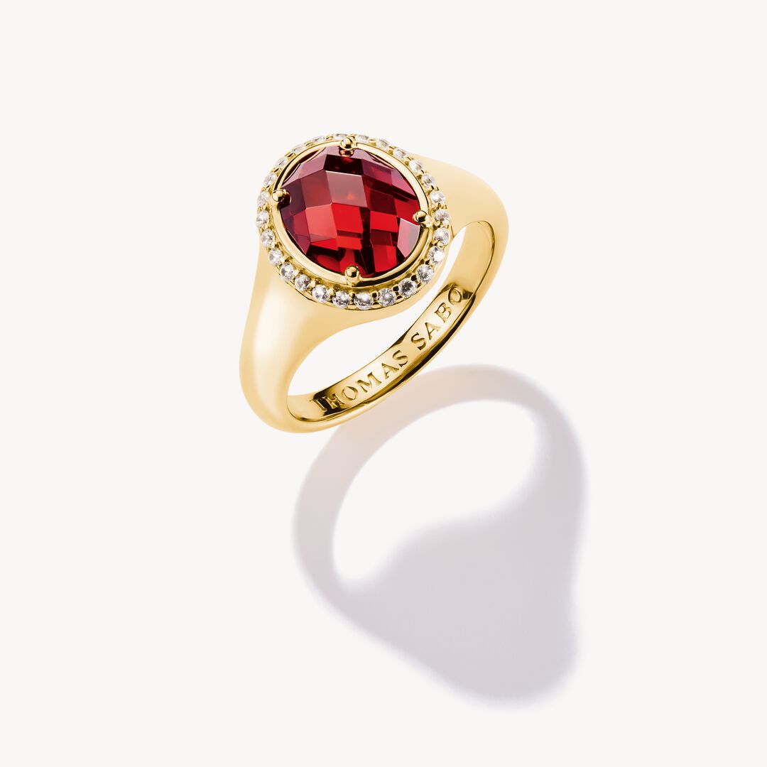 Gold ring with a red gemstone on a white background