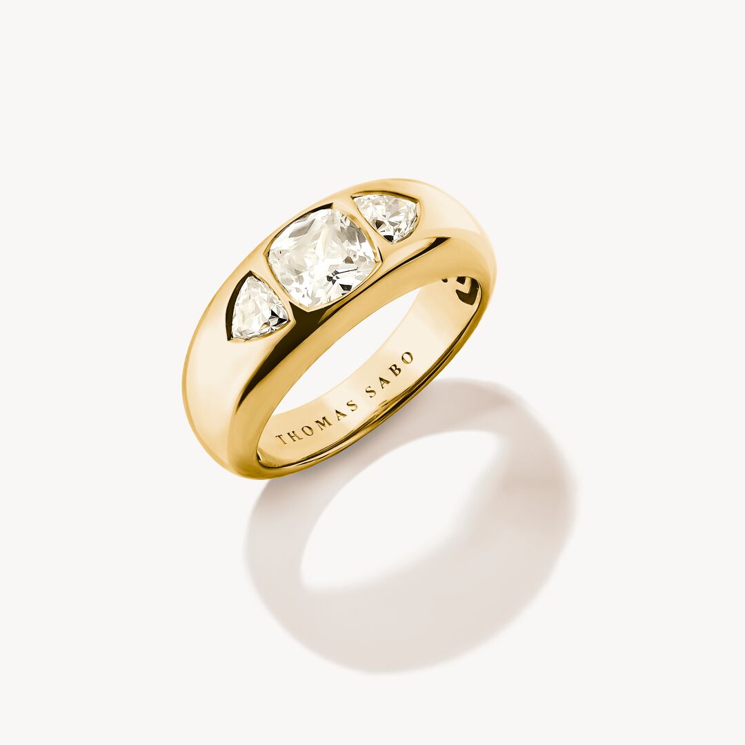 Gold ring with three clear gemstones on a white background, featuring the Thomas Sabo brand.